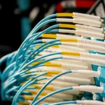 Perangkat sakelar fiber optik dengan kabel terhubung di ruang server sebagai ilustrasi teknologi broadband internet