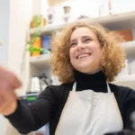 Barista tersenyum melayani pelanggan di kafe sebagai contoh pemenuhan kebutuhan pelanggan